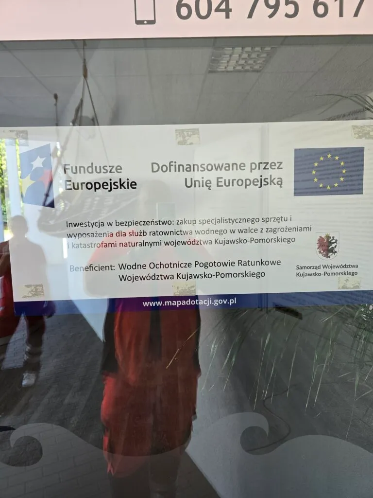 Plakat projektu unijnego naklejony na szklanych drzwiach przystani